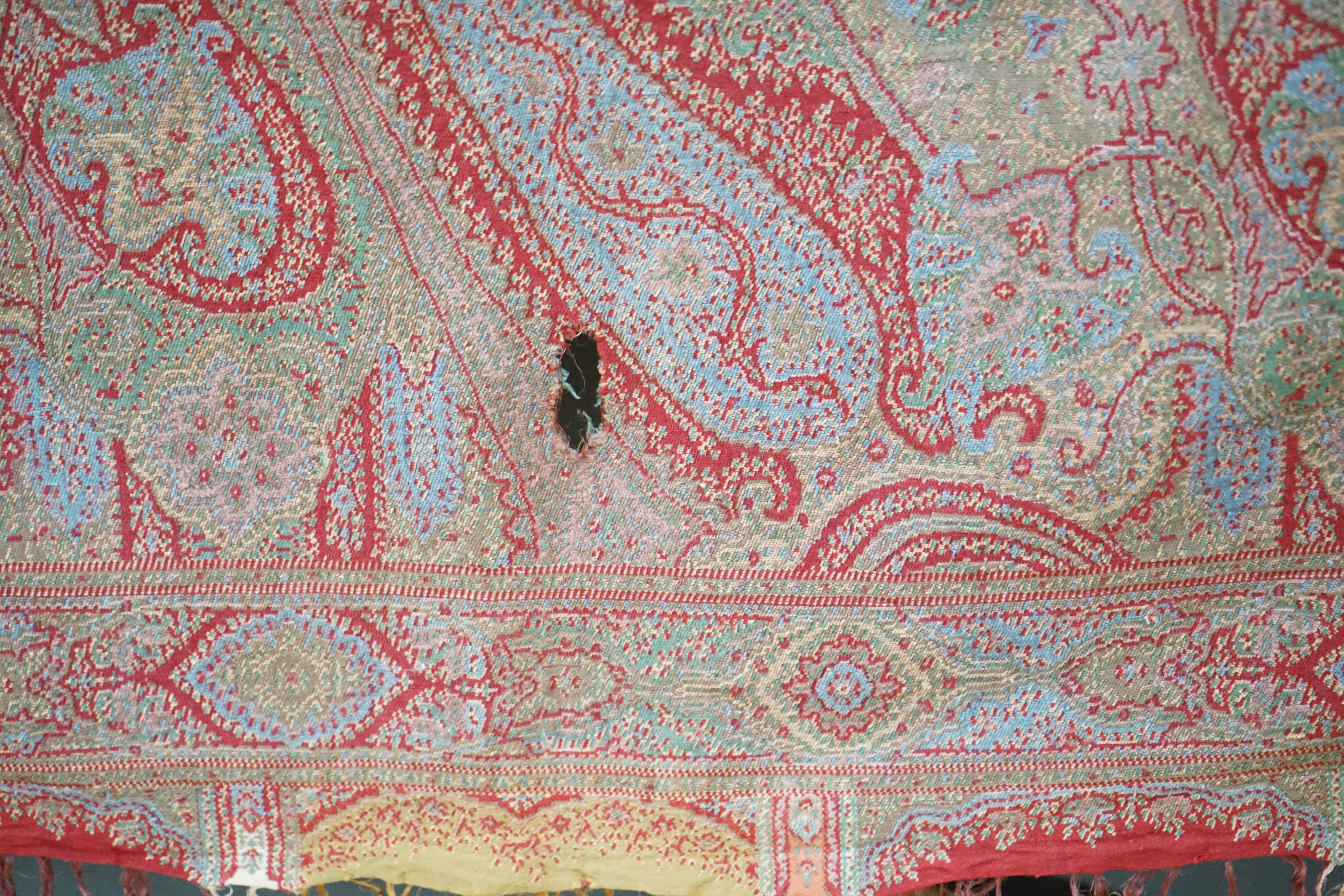 A 19th century wool and silk woven Paisley shawl, woven in a diagonal tear drop design, in reds, blues, greens, creams and ochres, with an all round woven border, tasselling both ends, 320cm long x 162cm wide. Condition